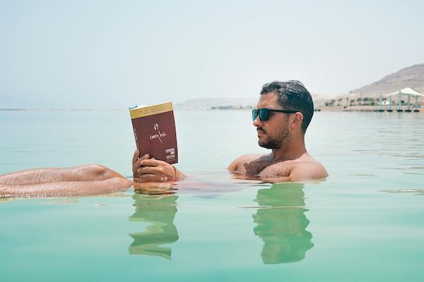 Man floating in mediterranean ocean reading a book