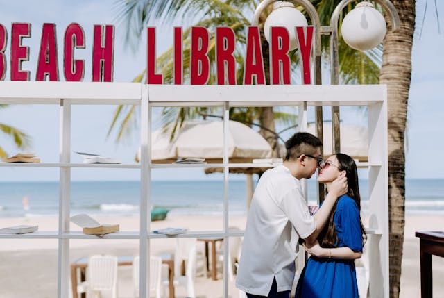 Couple on a beach kissing near a library stand