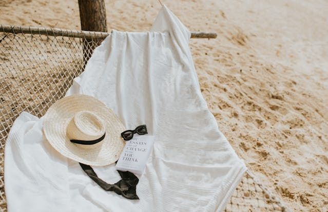 A hat, a book and a pair of sunglasses on a hammock