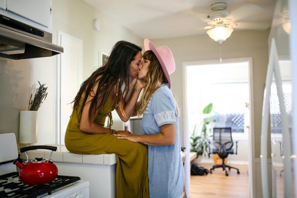 two young women kissing in a kitchen