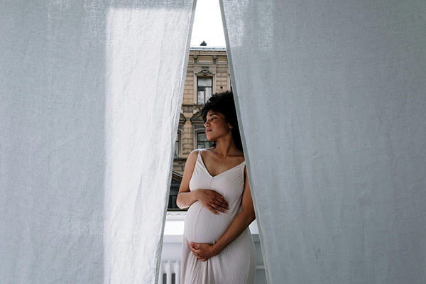 young pregnant woman in white dress in city