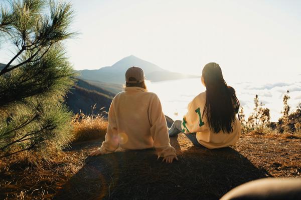 Two female friends watching the sunrise over a mountain