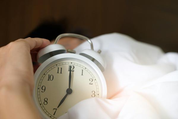 White alarm clock on a white bed spread