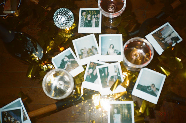 pile of polaroid photos on table with glasses of wine